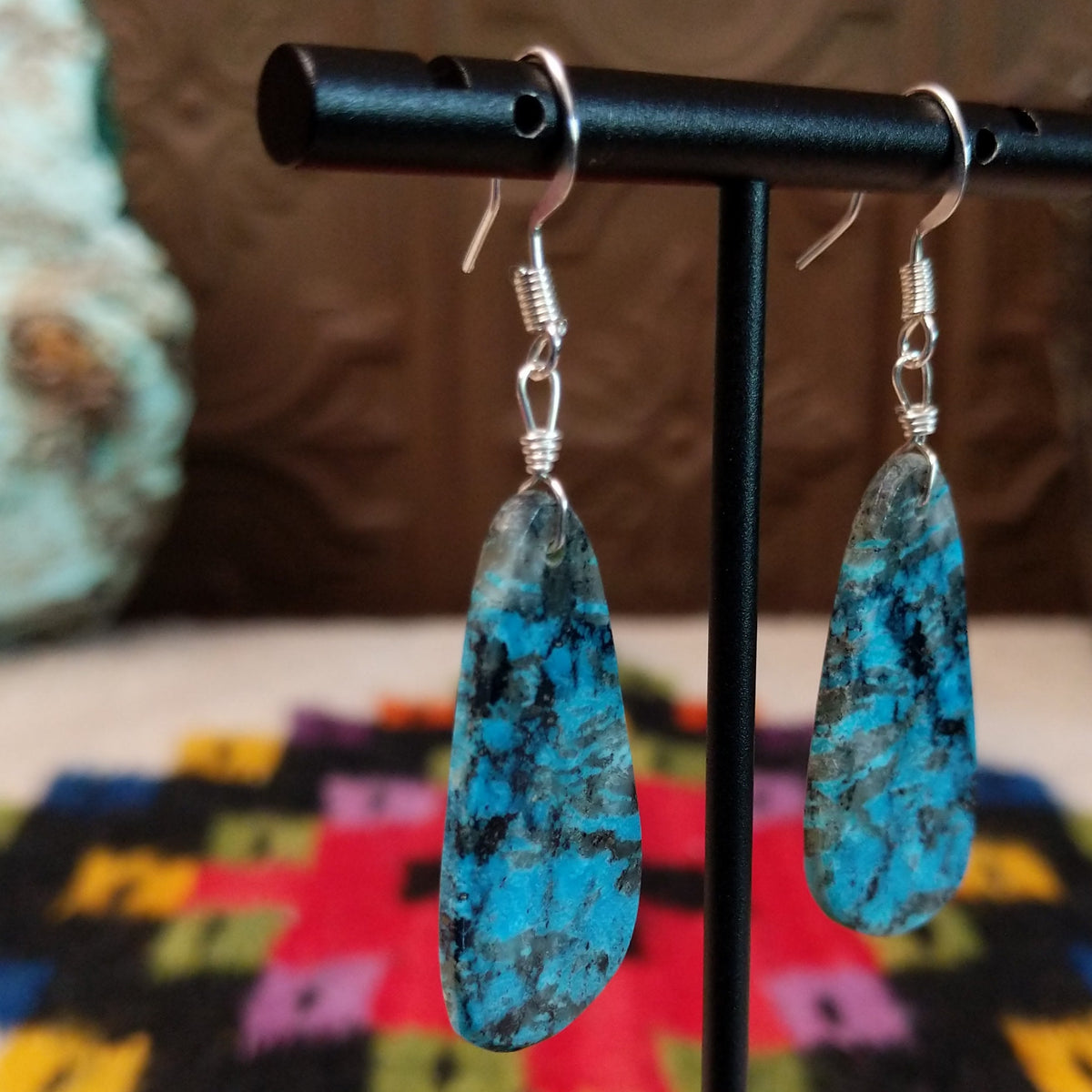 Navajo Dark Matrix Slab Turquoise Earrings featuring elongated blue turquoise stones with bold black and gray matrix patterns, suspended from silver hooks; side view.