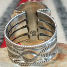Navajo turquoise ring featuring a large oval bright blue turquoise stone with dark matrix, framed by twisted silver rope and an ornate scalloped silver setting; artisan and Sterling Silver stamp.