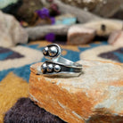 Handcrafted Navajo sterling silver bypass ring featuring graduated polished silver domes set in oxidized open-ended bezels, creating a modern Southwestern statement design; side view.
