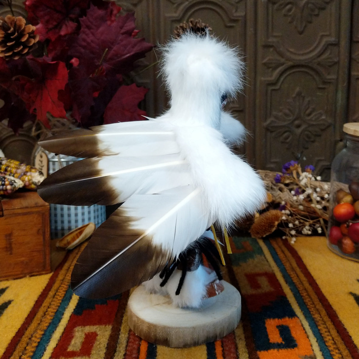 Side view of the Navajo Eagle Kachina doll with wide outstretched white feather wings, white fur headdress, black painted facial markings, and white fabric apron.