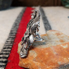 Navajo silver ring with layered feathers, flowers, and curled wire accents.