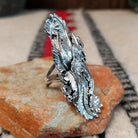 Navajo silver ring with layered feathers, flowers, and curled wire accents.