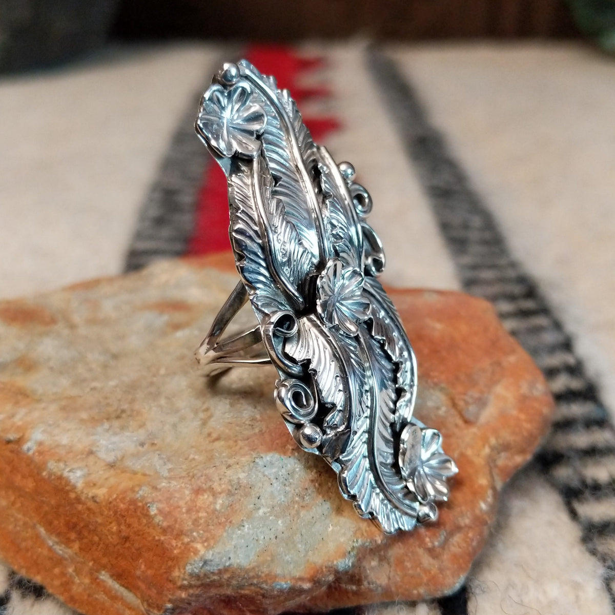 Navajo silver ring with layered feathers, flowers, and curled wire accents.