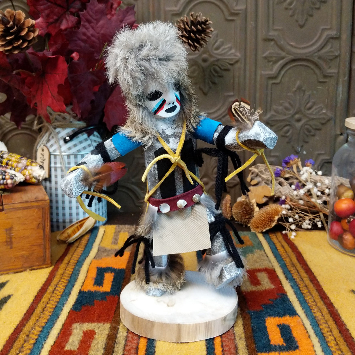 Navajo Field House Kachina doll with oversized fur headdress, painted white face, blue sleeves, and outstretched arms.
