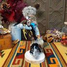 Side view of the Navajo Field House Kachina doll with oversized fur headdress, painted white face, blue sleeves, and outstretched arms.
