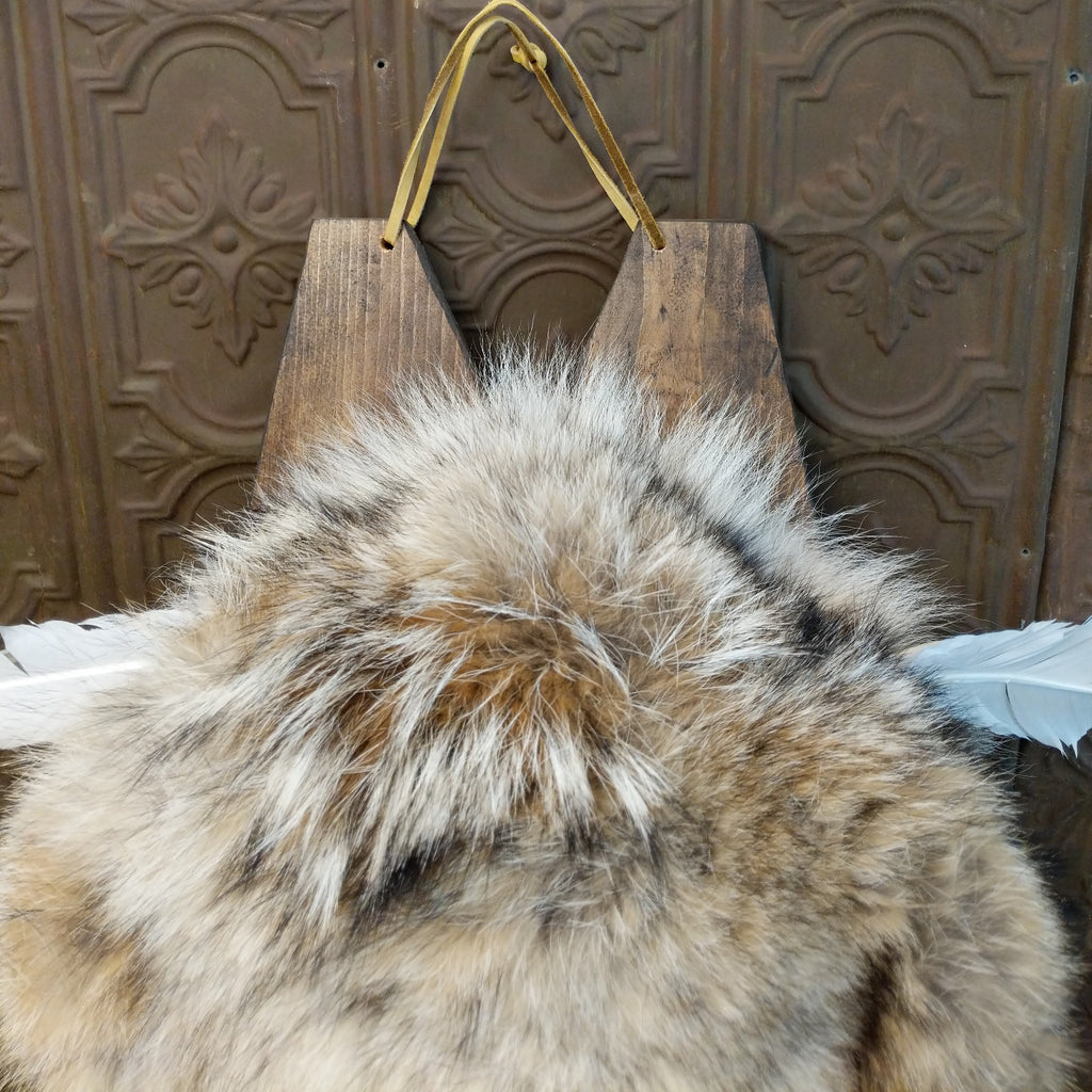 Fox fur, wood, and leather crafted into a cradlebaord with feathers and decorative beading.