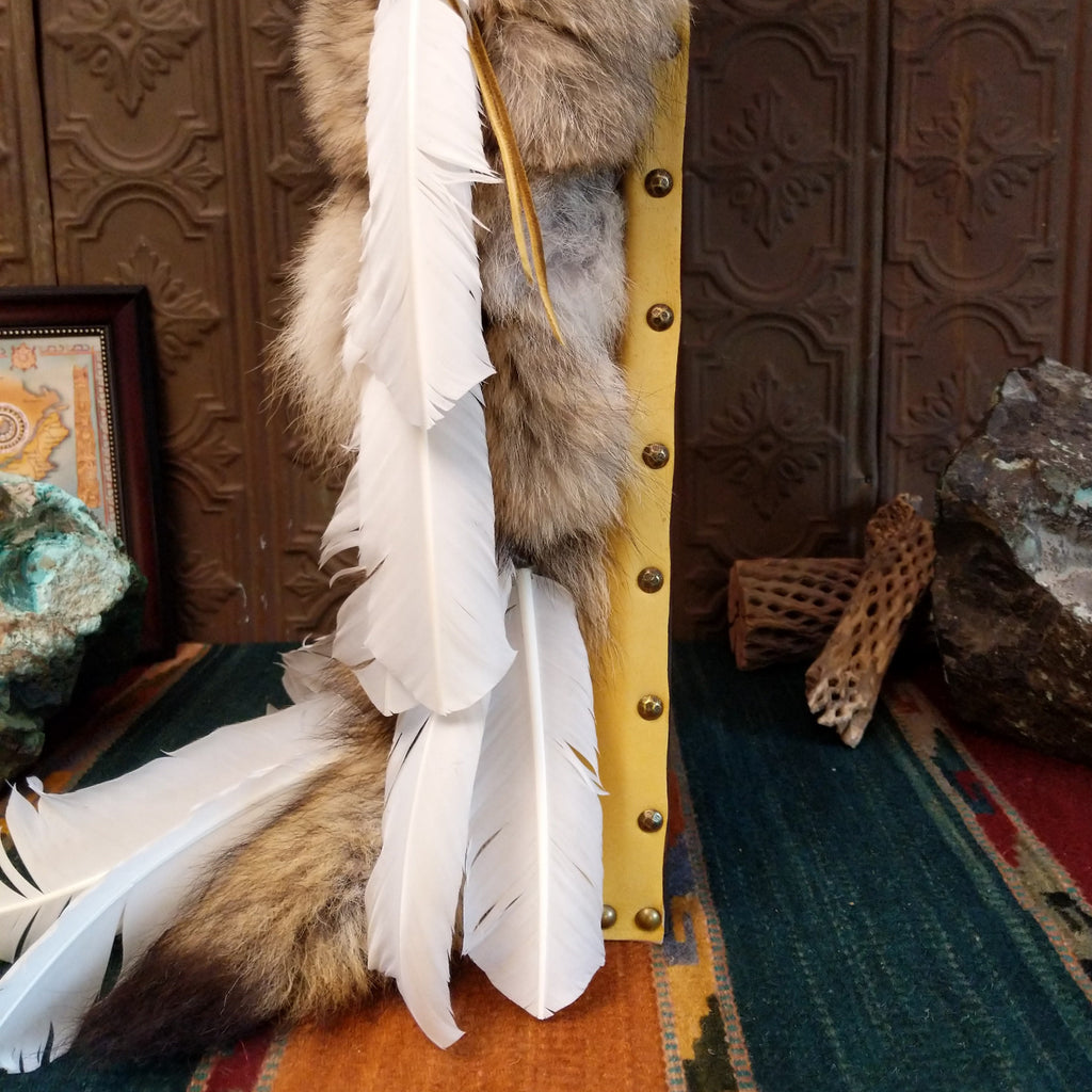 A close-up of the brass beads and feathers on the side of the piece.