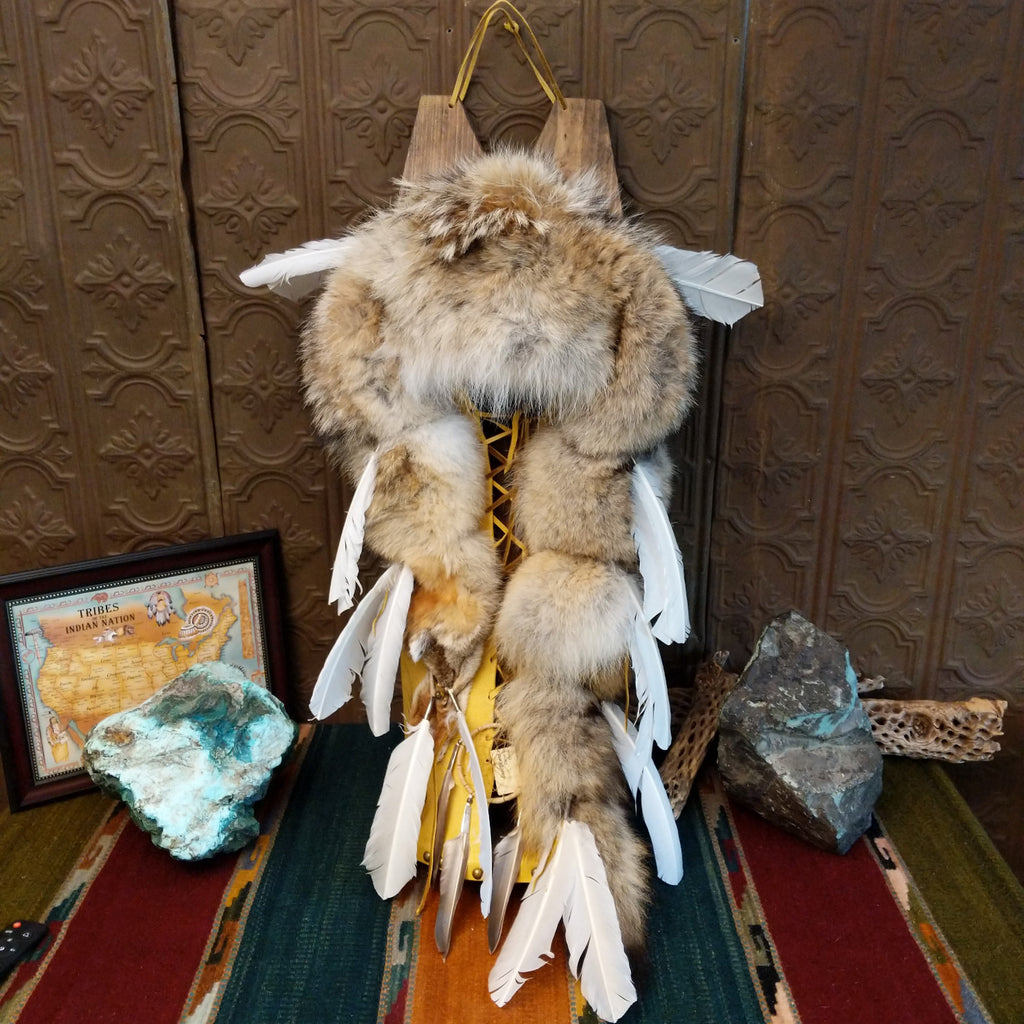 Fox fur, wood, and leather crafted into a cradlebaord with feathers and decorative beading.