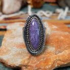 Navajo sterling silver ring featuring an elongated purple charoite stone framed by twisted silver rope and detailed radiating silverwork.