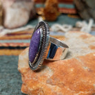 Navajo sterling silver ring featuring an elongated purple charoite stone framed by twisted silver rope and detailed radiating silverwork; side view.