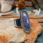 Navajo sterling silver ring featuring an elongated purple charoite stone framed by twisted silver rope and detailed radiating silverwork; side view.