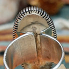 Navajo sterling silver ring featuring an elongated purple charoite stone framed by twisted silver rope and detailed radiating silverwork; artisan and Sterling Silver stamp.