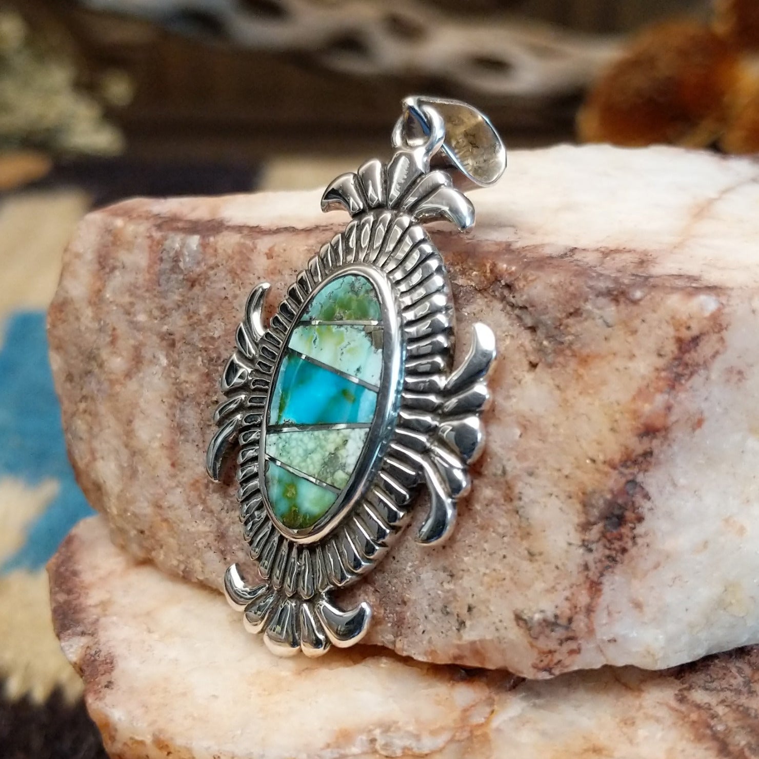 Sterling silver pendant with turquoise inlaid in the oval bezel, framed by fanned silverwork.