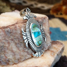 Sterling silver pendant with turquoise inlaid in the oval bezel, framed by fanned silverwork.