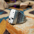 Sterling silver White Buffalo ring by J.P. featuring a rectangular White Buffalo stone with black veining, serrated bezel, and grooved split-shank Southwestern design; side view.