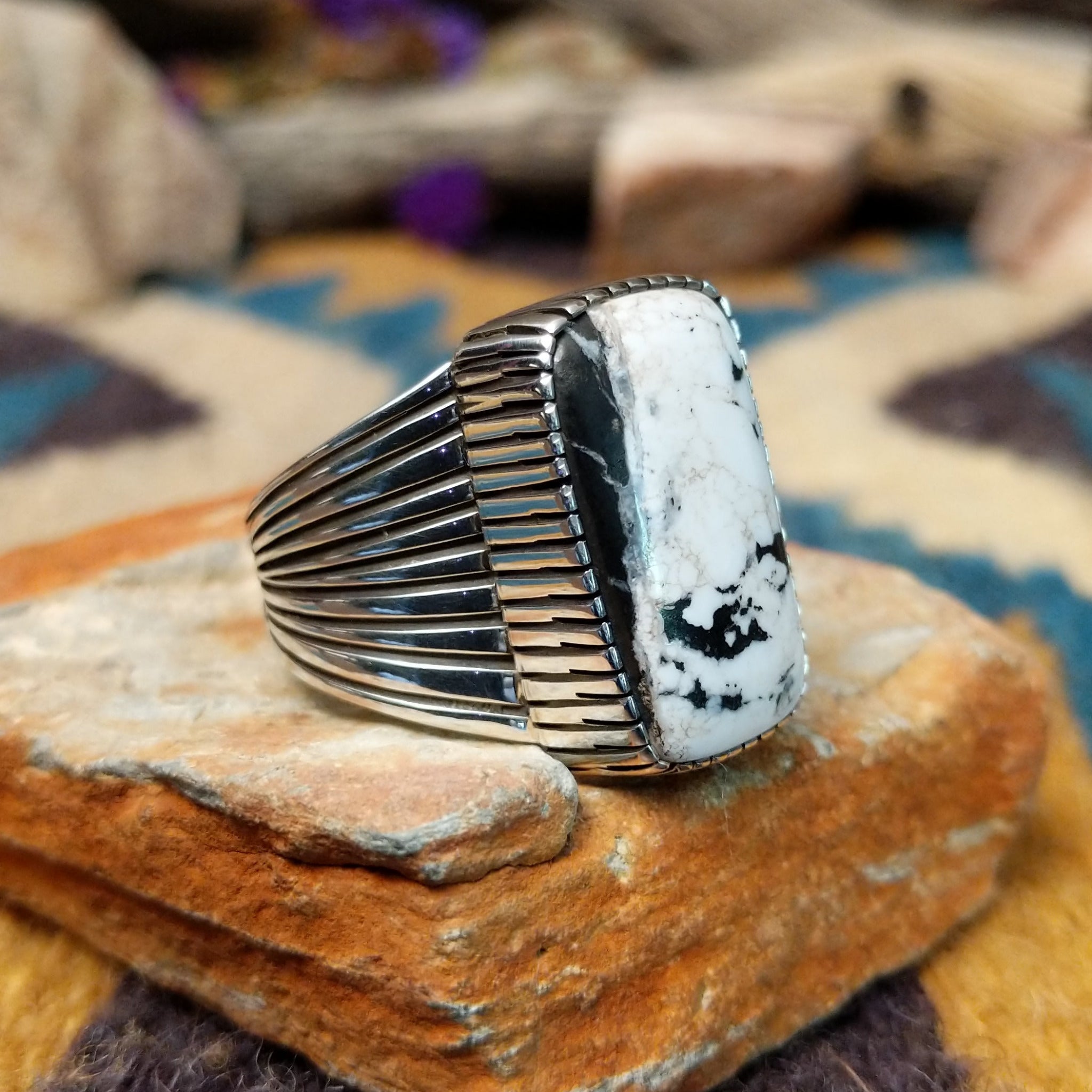 Sterling silver White Buffalo ring by J.P. featuring a rectangular White Buffalo stone with black veining, serrated bezel, and grooved split-shank Southwestern design; side view.