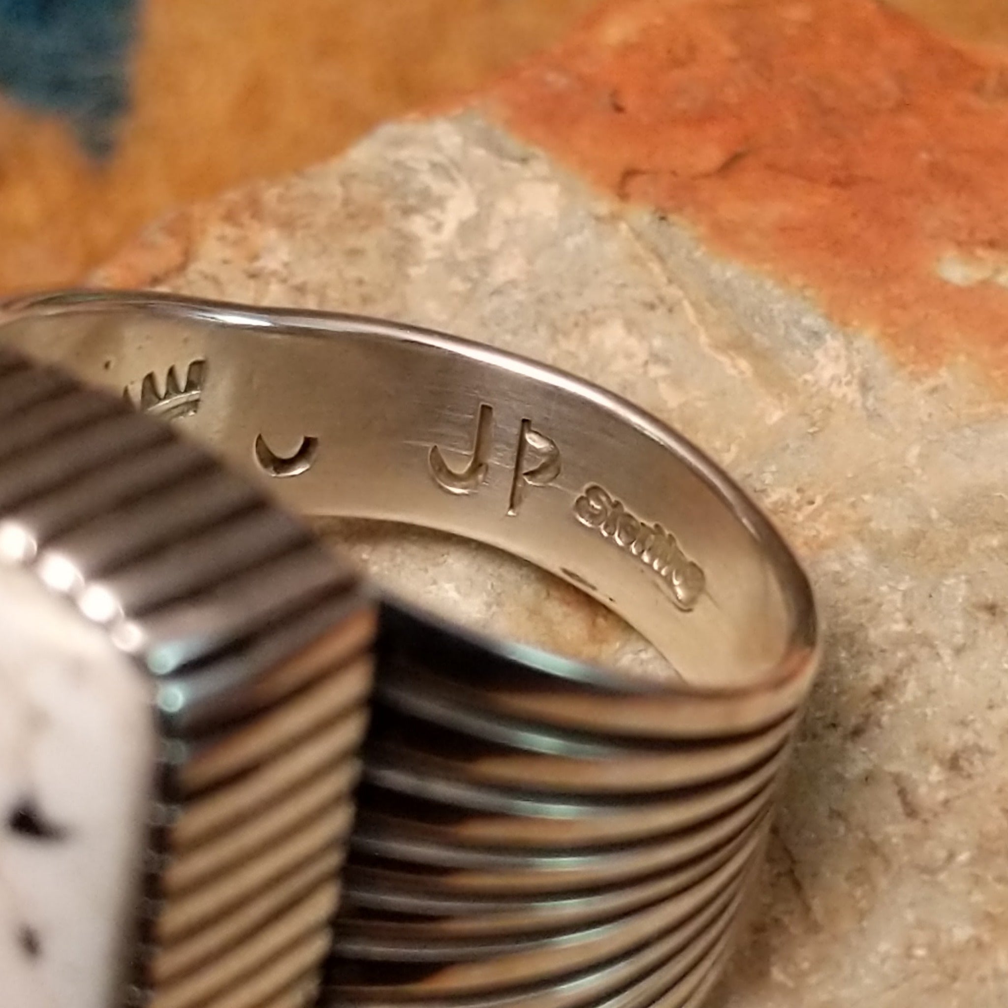 Sterling silver White Buffalo ring by J.P. featuring a rectangular White Buffalo stone with black veining, serrated bezel, and grooved split-shank Southwestern design; artisan and Sterling Silver stamp.