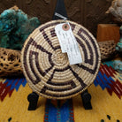 Navajo handwoven patterned basket by Louise with a geometric spiral design in natural and dark dyed fibers.