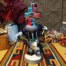 This vibrant Navajo Hemis Kachina by Debbie James features a hand-painted red and turquoise mask, stepped headdress, natural feathers, soft fur accents, leather ties, and a circular wooden display base.