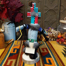 This vibrant Navajo Hemis Kachina by Debbie James features a hand-painted red and turquoise mask, stepped headdress, natural feathers, soft fur accents, leather ties, and a circular wooden display base; back view.