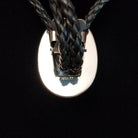 Navajo Kingman Turquoise Bolo Tie featuring a large oval sky-blue turquoise stone with golden-brown matrix, decorative silver bezel, braided black leather cord, and polished silver tips; backside view of Bolo with Sterling Silver stamp.