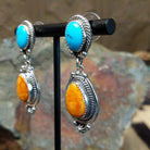 Handcrafted sterling silver Navajo Kingman turquoise and orange spiny oyster earrings, featuring a two-stone dangle design with traditional rope and stamped silver details; side view.