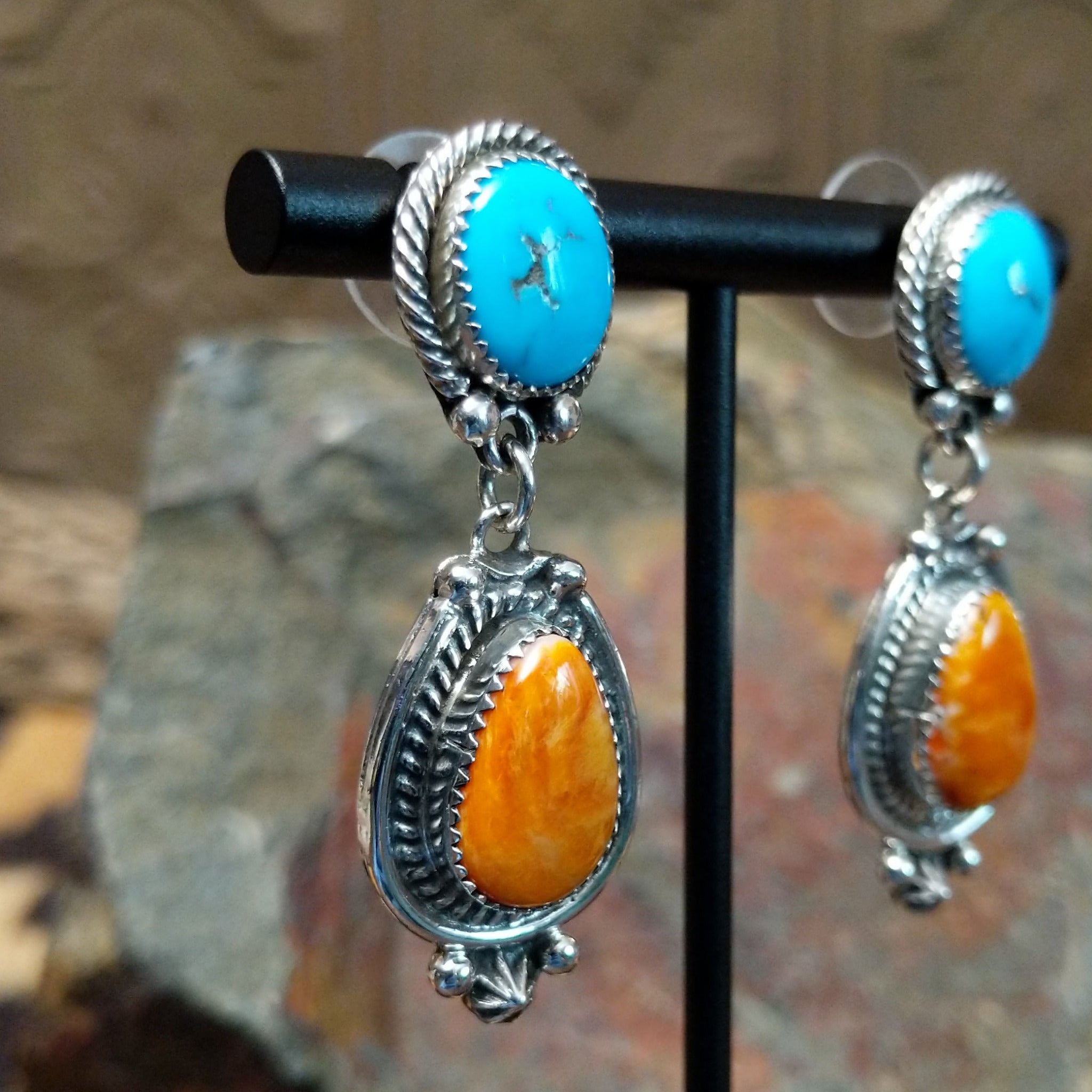 Handcrafted sterling silver Navajo Kingman turquoise and orange spiny oyster earrings, featuring a two-stone dangle design with traditional rope and stamped silver details; side view.