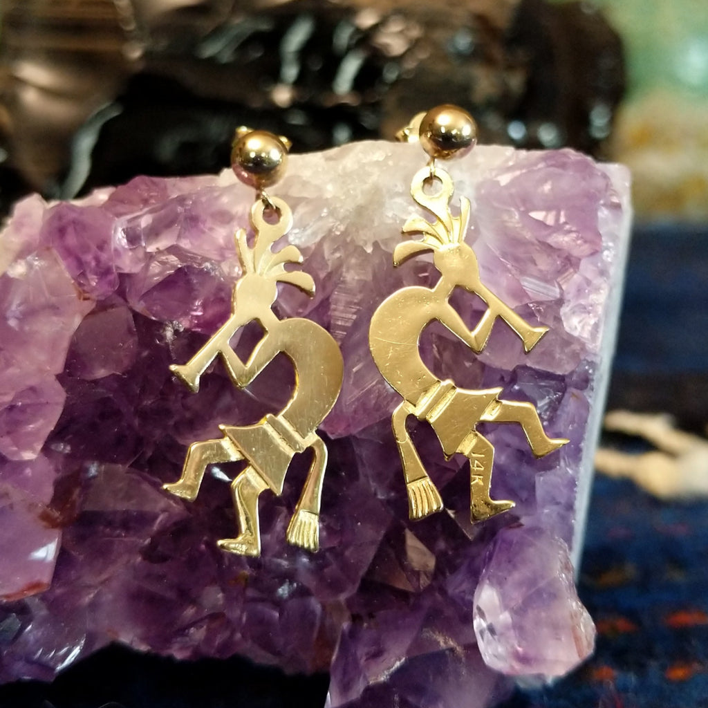 Pair of gold earrings shaped like Kokopelli figures and polished.