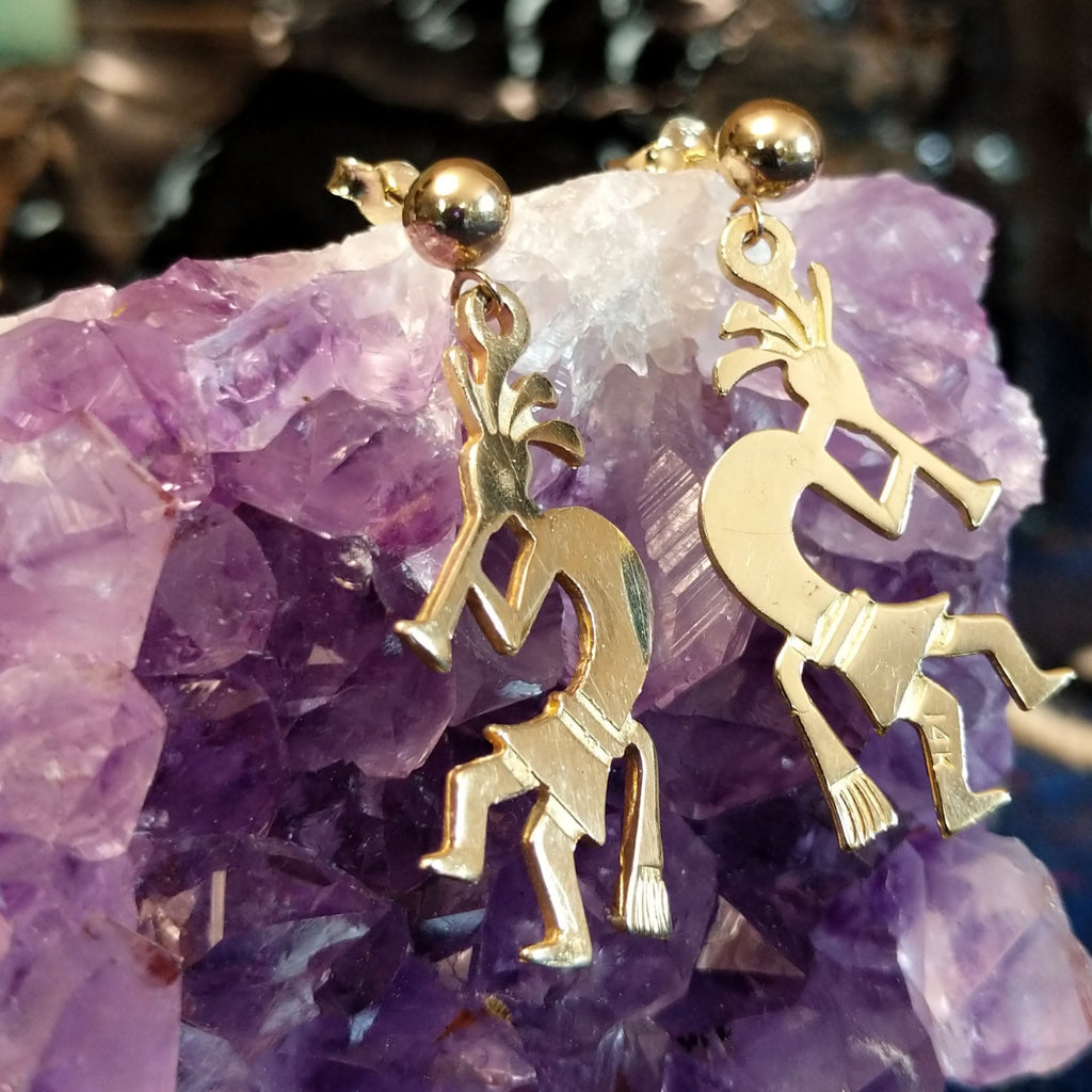 Pair of gold earrings shaped like Kokopelli figures and polished.