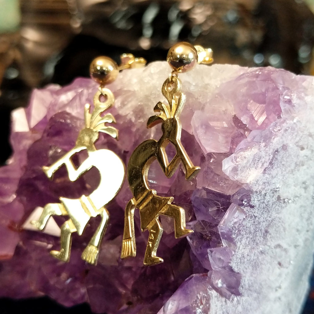 Pair of gold earrings shaped like Kokopelli figures and polished.