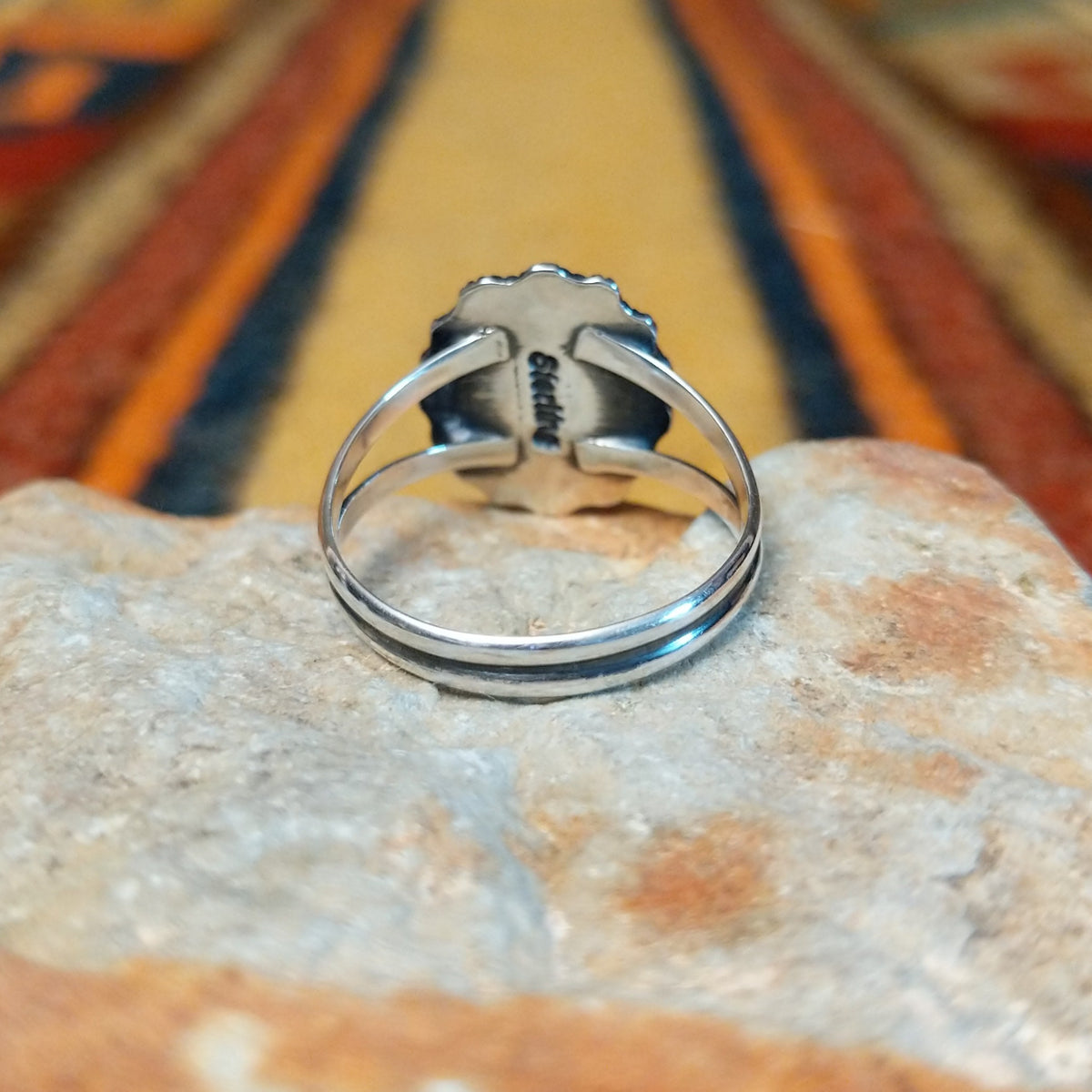 Rear view of a silver lapis lazuli ring showing the underside of the scalloped oval setting, a split-shank band, and an interior "sterling" stamp.