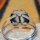 Rear view of a silver lapis lazuli ring showing the underside of the scalloped oval setting, a split-shank band, and an interior "sterling" stamp.