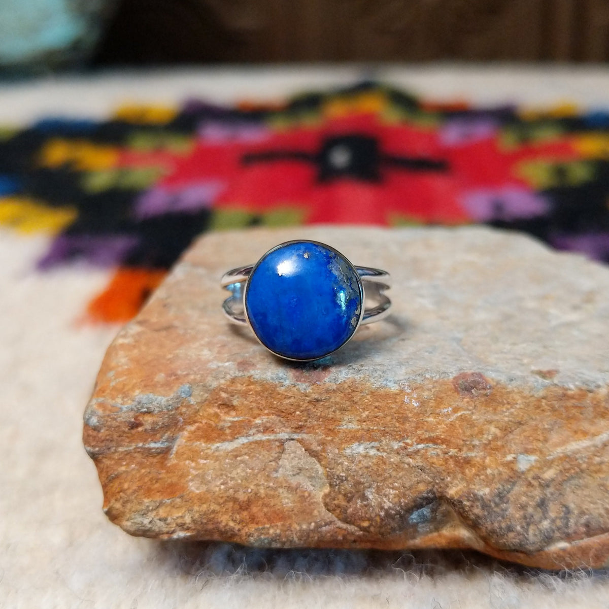 This captivating Navajo Lapis Round Ring features a polished round royal-blue lapis stone with natural mineral markings, set in a simple silver bezel with an open split-shank band.