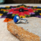 This captivating Navajo Lapis Round Ring features a polished round royal-blue lapis stone with natural mineral markings, set in a simple silver bezel with an open split-shank band; side view.