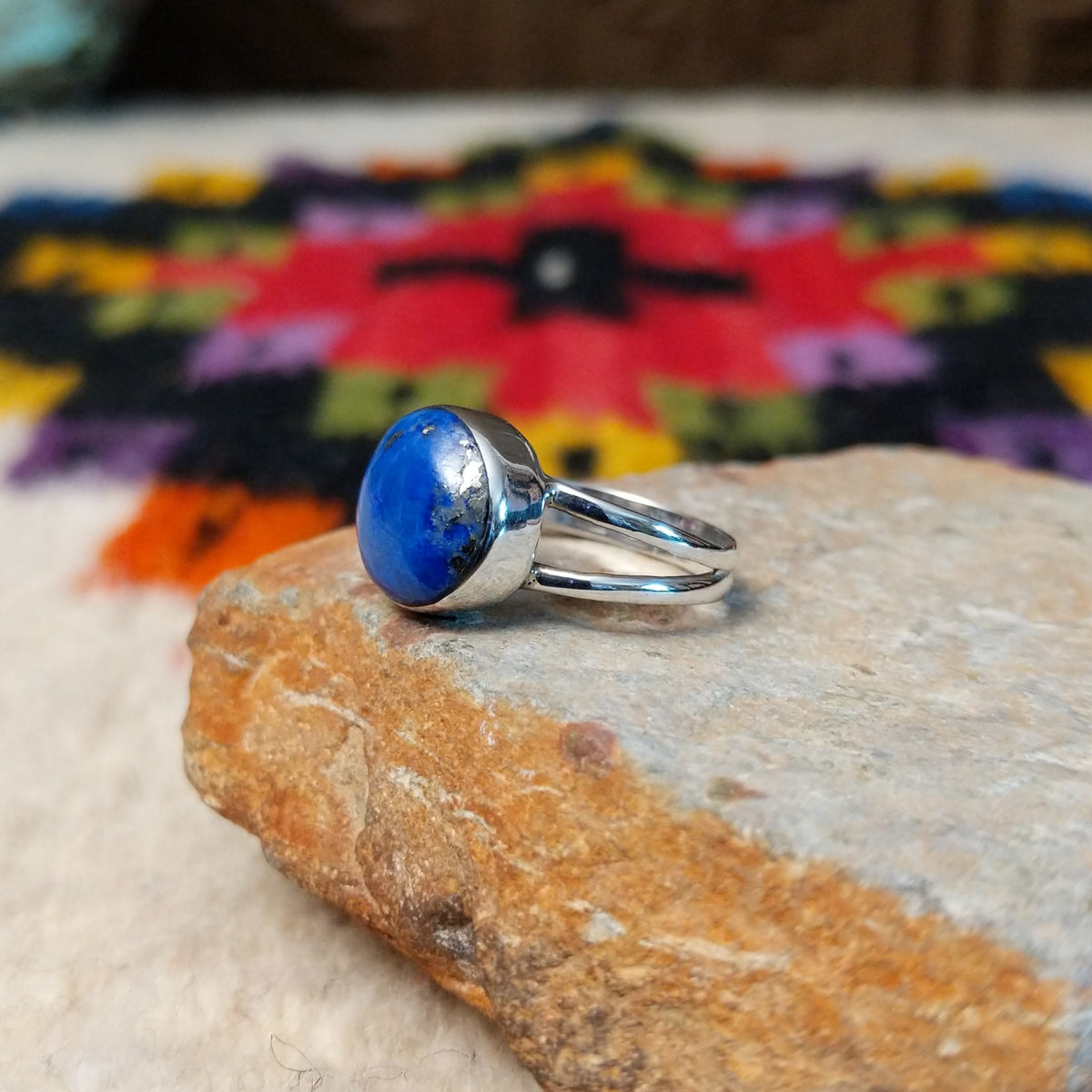 This captivating Navajo Lapis Round Ring features a polished round royal-blue lapis stone with natural mineral markings, set in a simple silver bezel with an open split-shank band; side view.