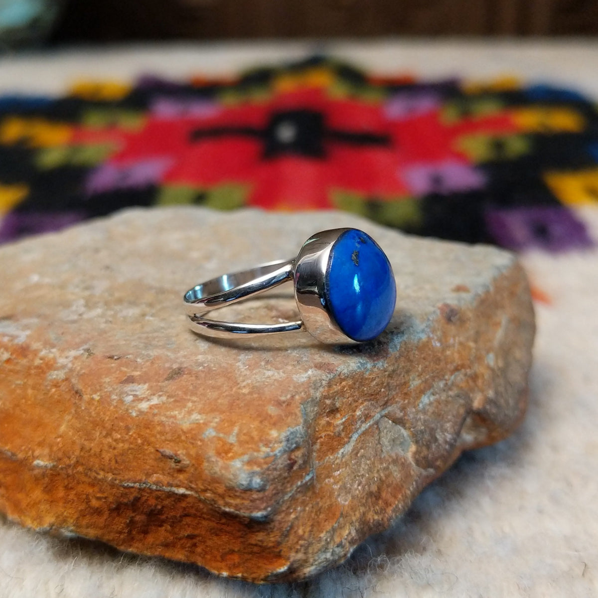 This captivating Navajo Lapis Round Ring features a polished round royal-blue lapis stone with natural mineral markings, set in a simple silver bezel with an open split-shank band; side view.