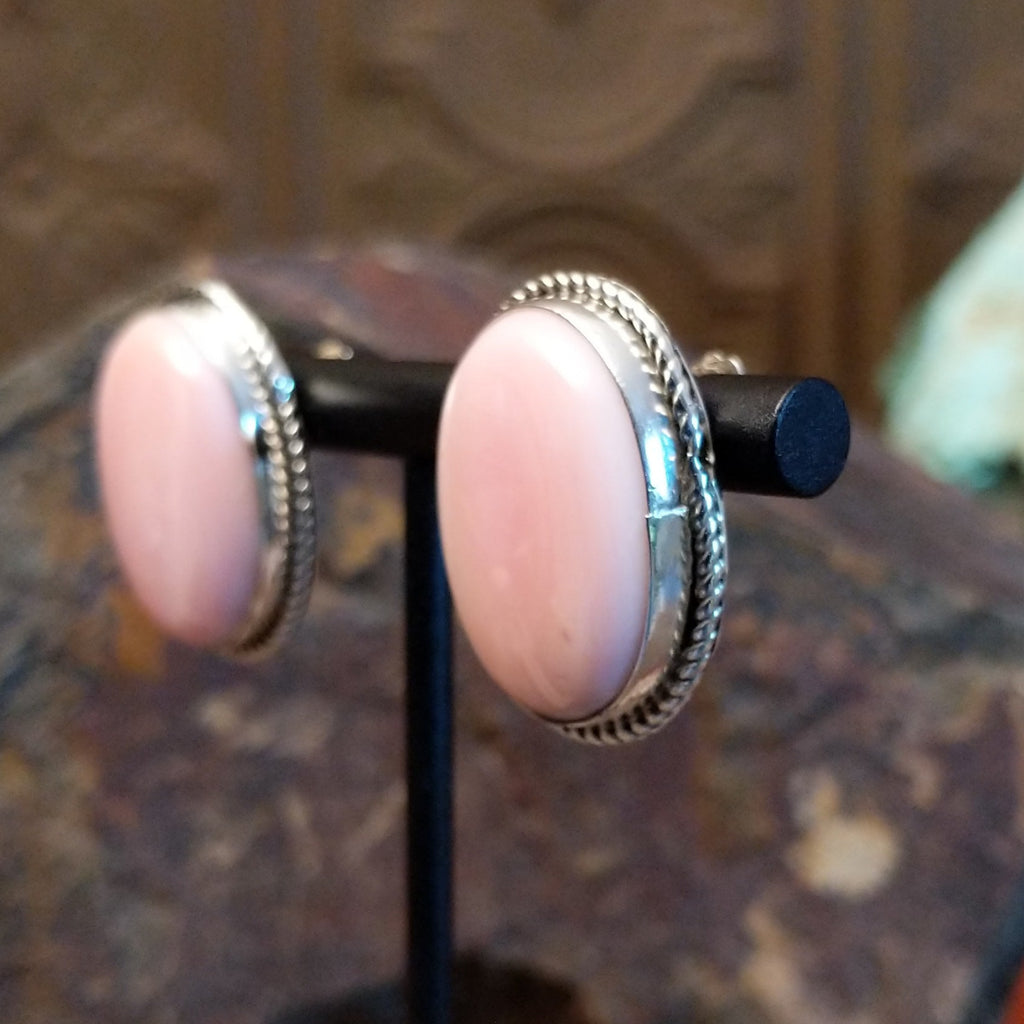 Large pink conch shell set within a sterling silver bezel with twisted rope accents.