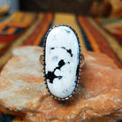 Navajo Large White Buffalo Ring featuring an elongated oval white stone with bold black matrix patterns, surrounded by a decorative notched silver bezel in a classic Southwestern statement design.