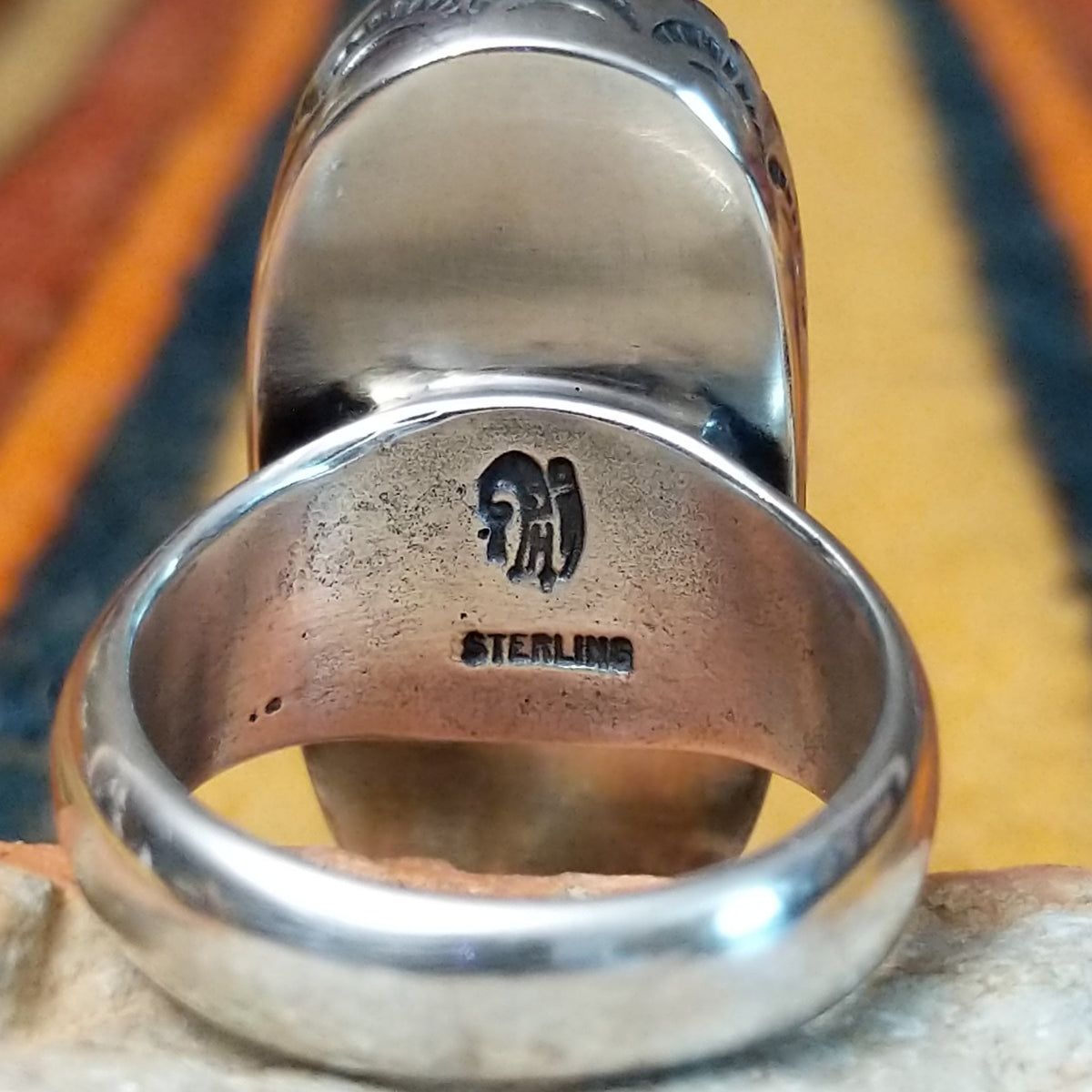 Navajo Large White Buffalo Ring featuring an elongated oval white stone with bold black matrix patterns, surrounded by a decorative notched silver bezel in a classic Southwestern statement design; artisan and Sterling Silver stamp.