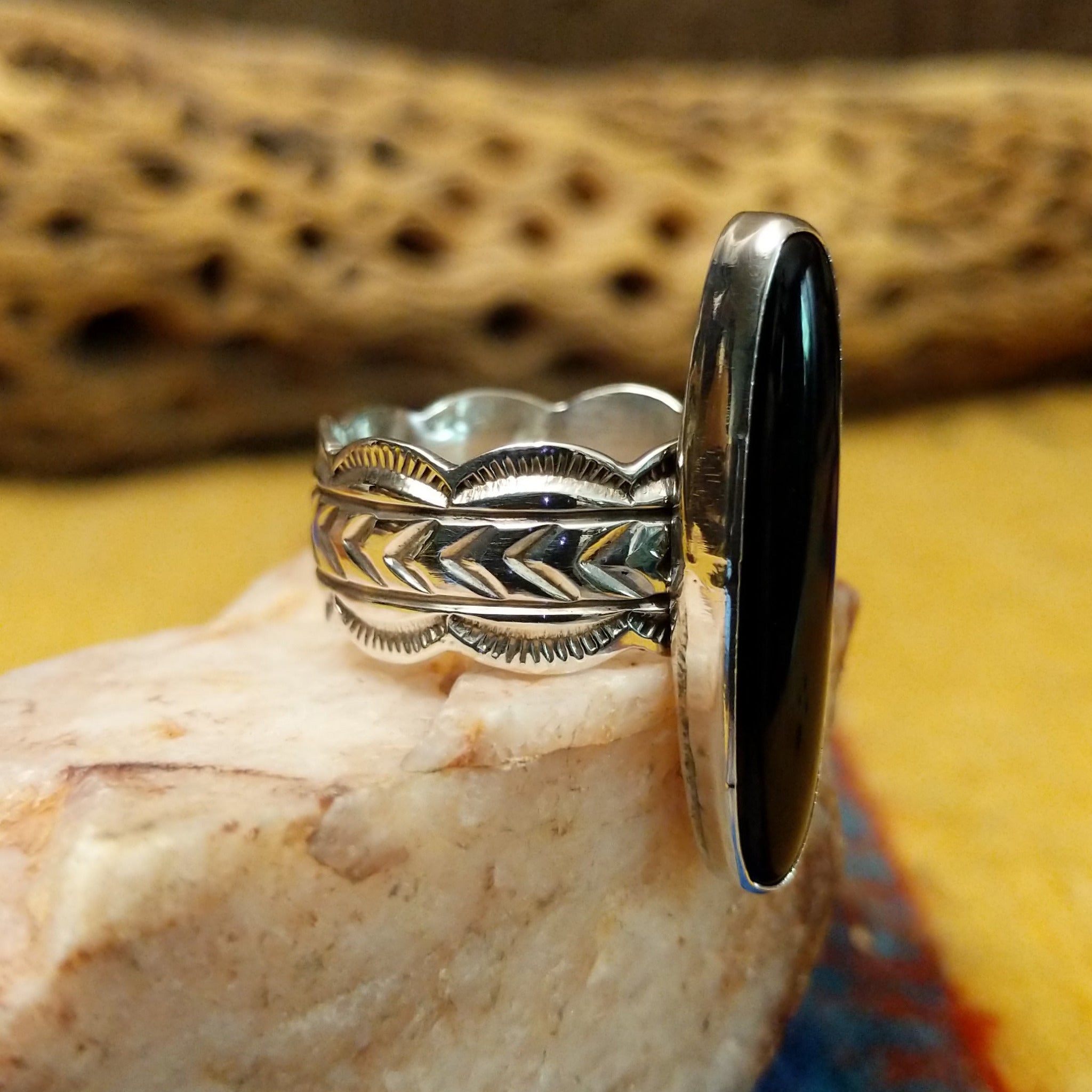 Navajo long black onyx ring, featuring an elongated black onyx stone set in a handcrafted sterling silver ring with an intricately detailed band.  Side view.