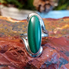 Sterling silver ring with looped band and long, oval malachite centerpiece.
