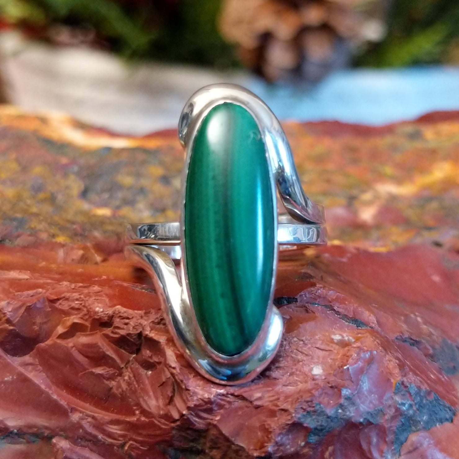 Sterling silver ring with looped band and long, oval malachite centerpiece.