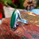 Sterling silver ring with looped band and long, oval malachite centerpiece.
