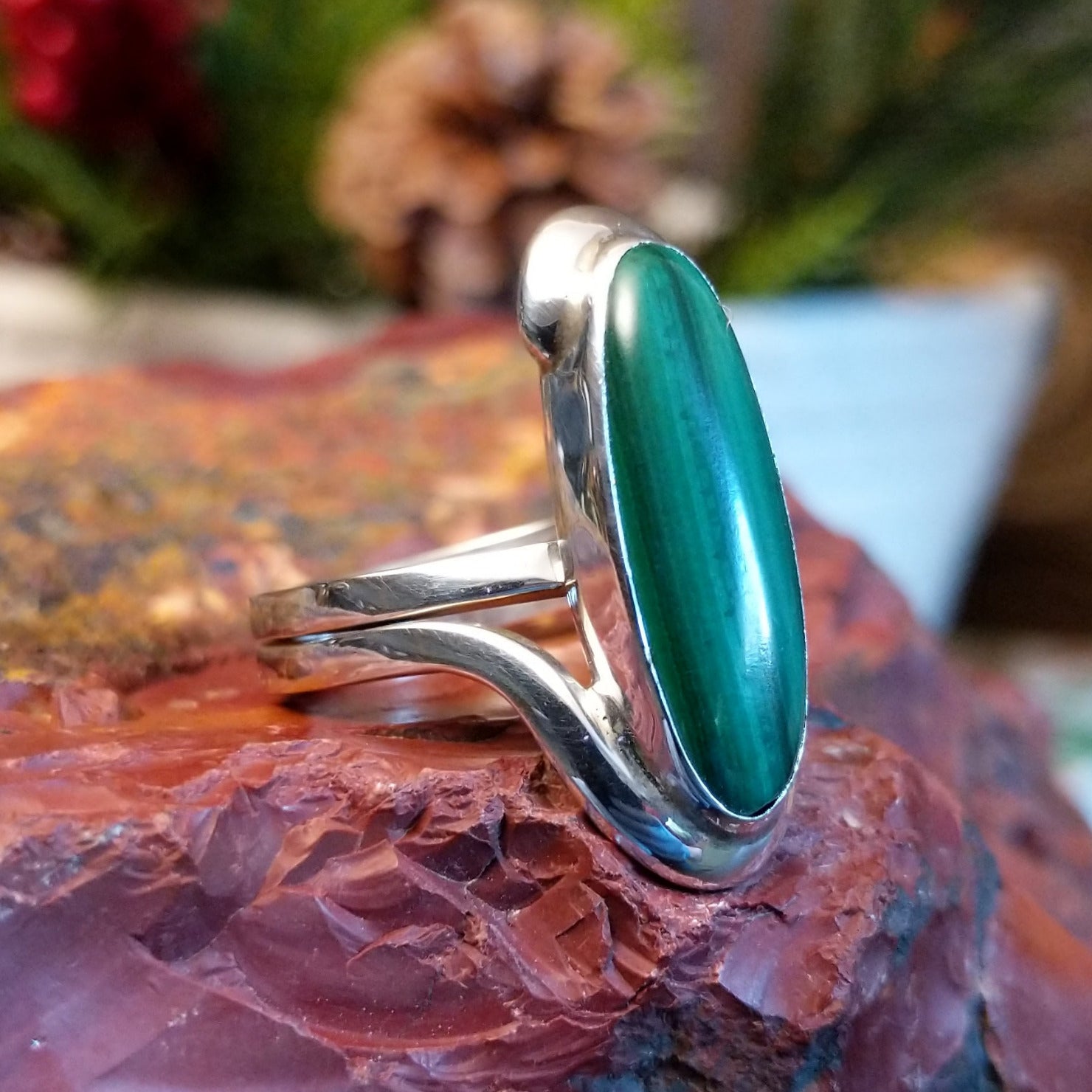 Sterling silver ring with looped band and long, oval malachite centerpiece.