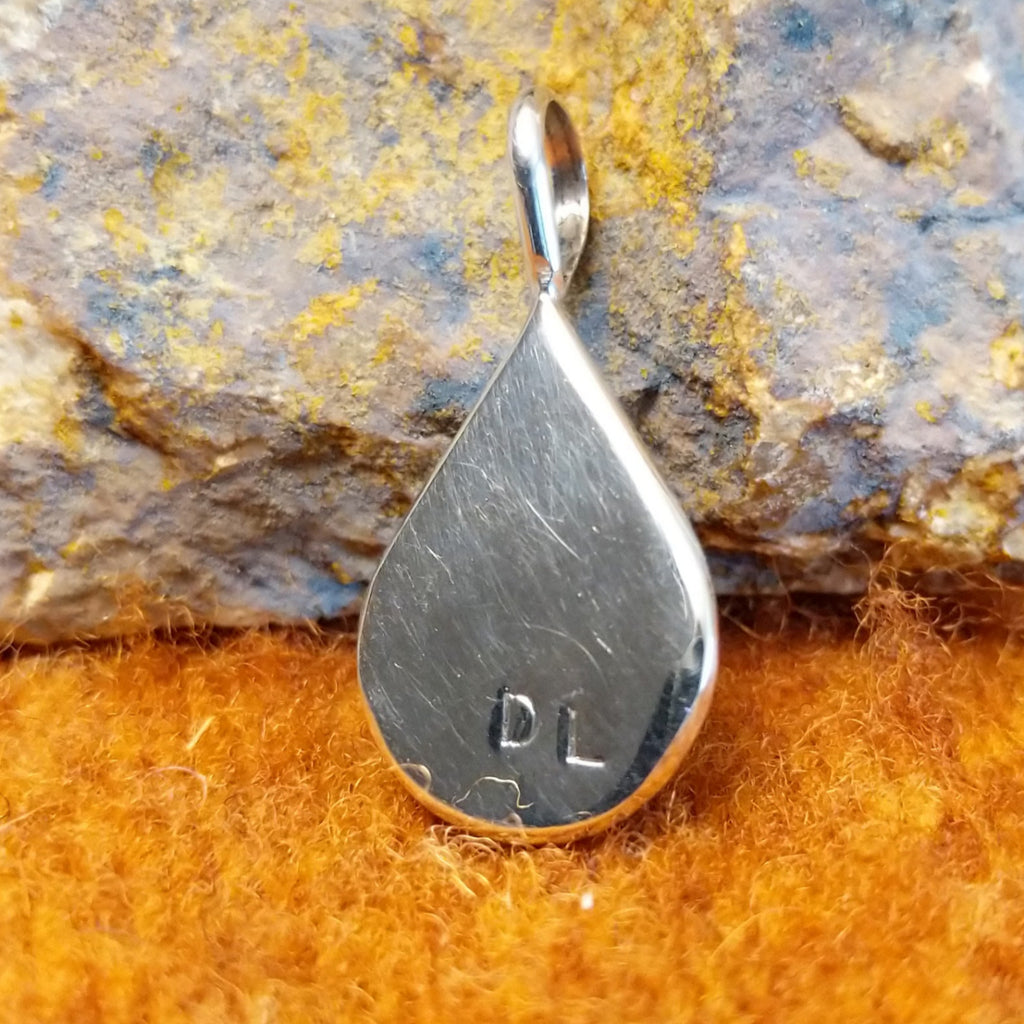 The back of the pendant features the artisan's initials stamped.