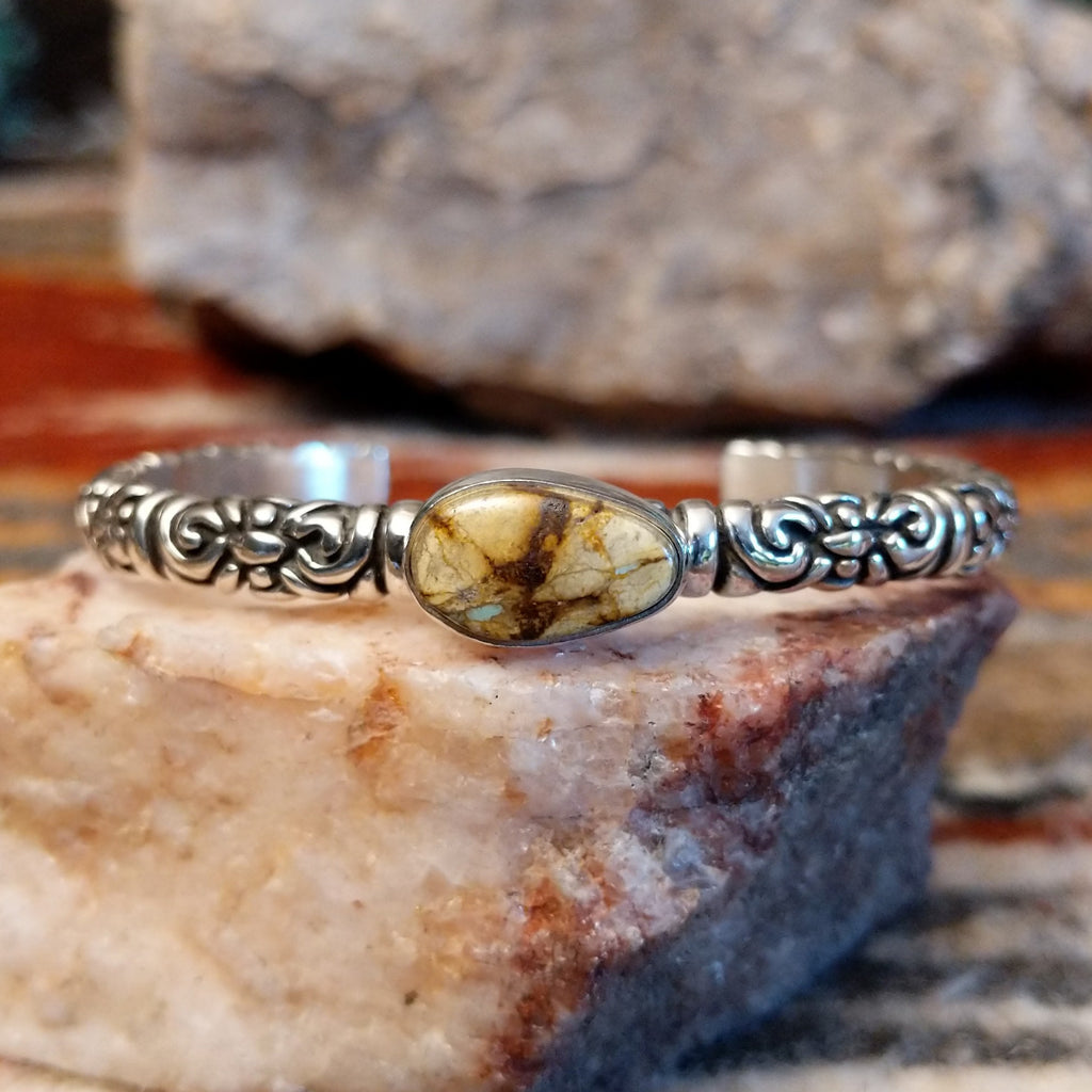 Boulder turquoise set in an oval bezel with intricate stamping on the band of the cuff.