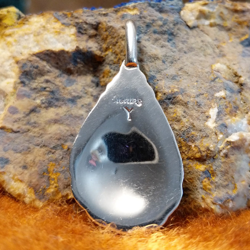 The back of the pendant features the artisan's initial.