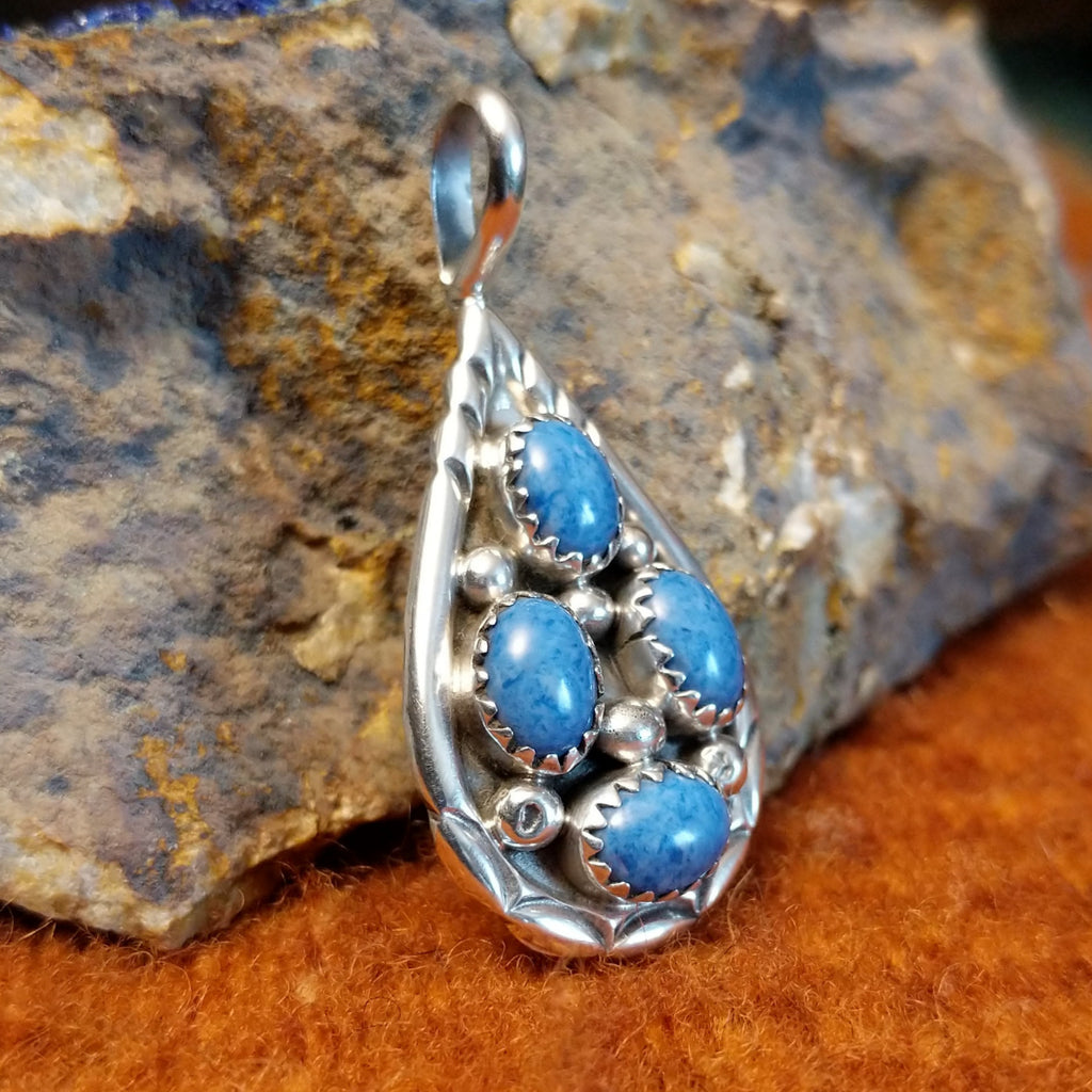 Four denim lapis stones set in notched sterling silver bezels on a sterling silver frame.