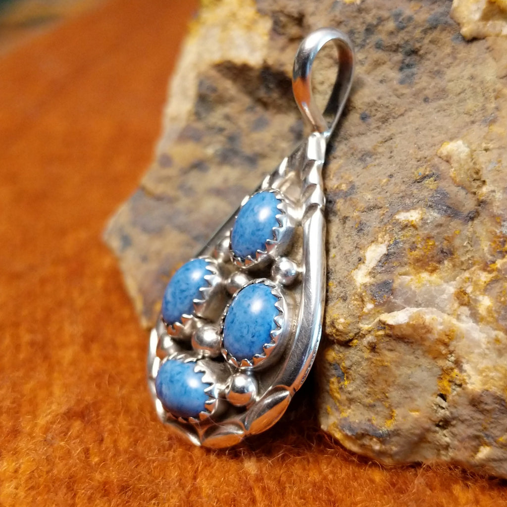 Four denim lapis stones set in notched sterling silver bezels on a sterling silver frame.