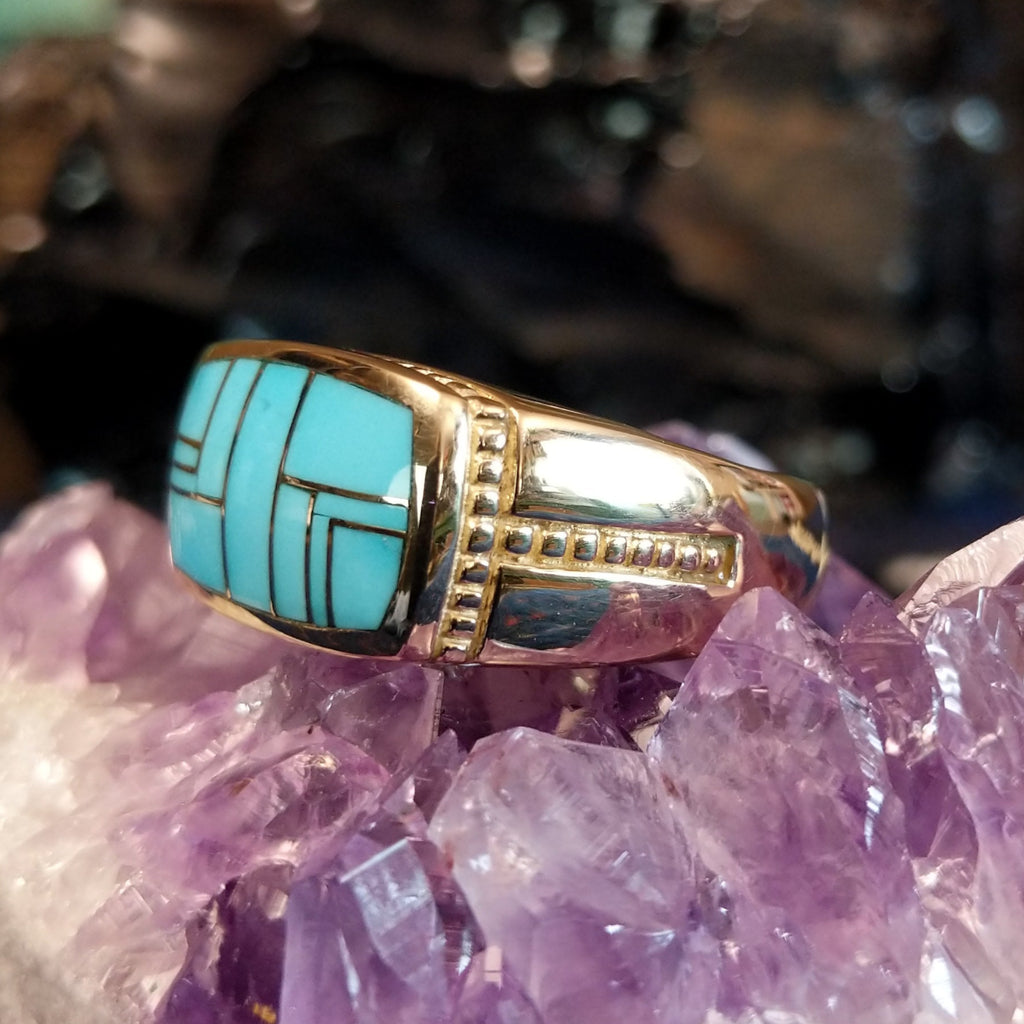 Gold ring featuring a rectangular turquoise inlay set in gold with a detailed band.